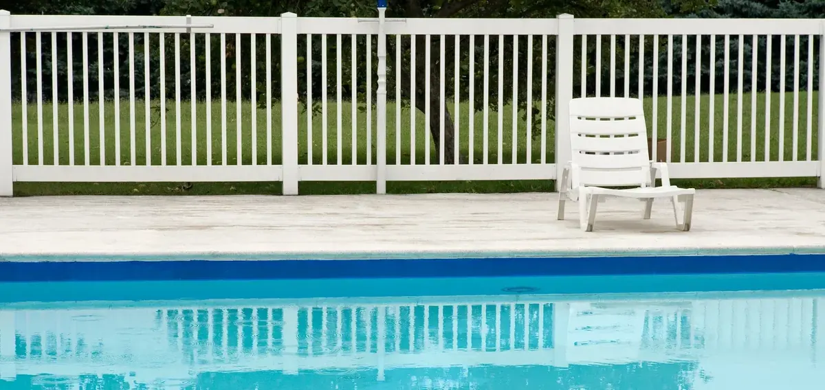 White picket pool fence enclosing a backyard swimming pool